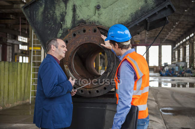 Responsabile e lavoratore che parla nel capannone della fabbrica — Foto stock