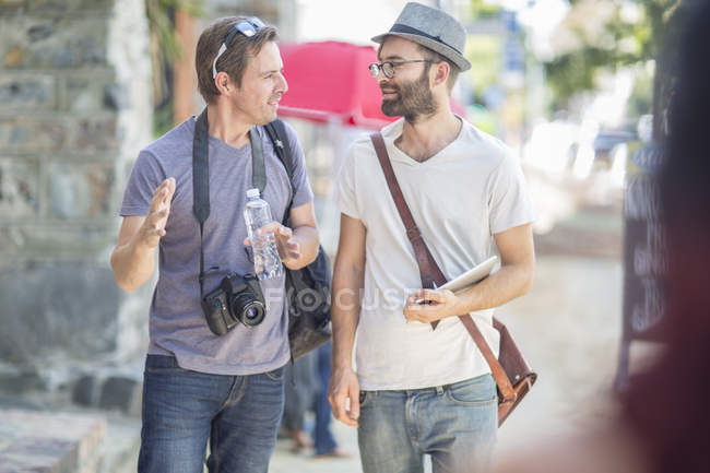 Due uomini che camminano e parlano in città — Foto stock
