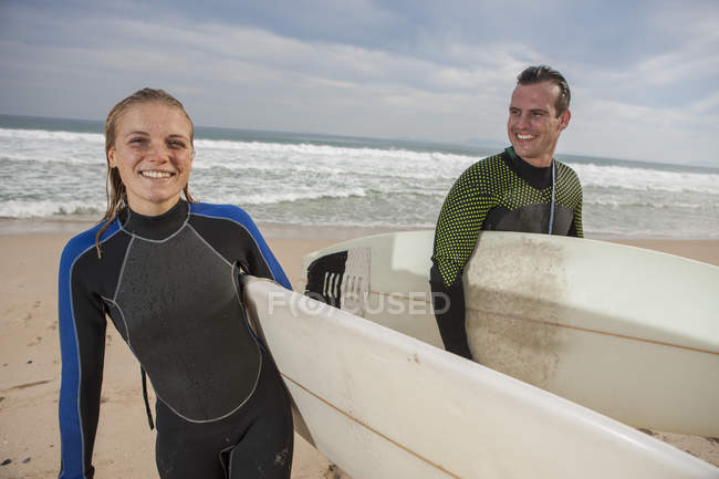 Smiling couple with surfboards on the beach — Stock Photo