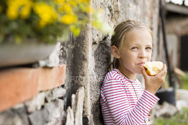 Portrait of smiling little girl eating apple — Stock Photo