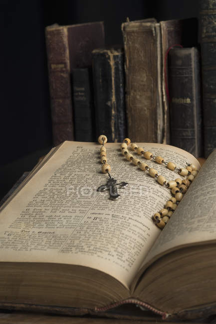 Libro aperto con rosario contro altri libri — Foto stock