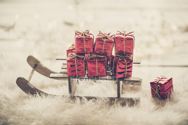 Miniatur trineo con pequeñas cajas de regalo de Navidad rojas - foto de stock