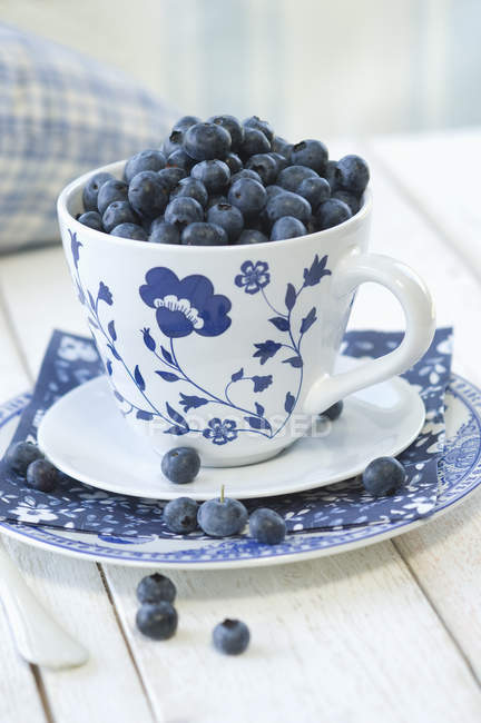 Closeup view of of blueberries in cup with flower ornament — Stock Photo