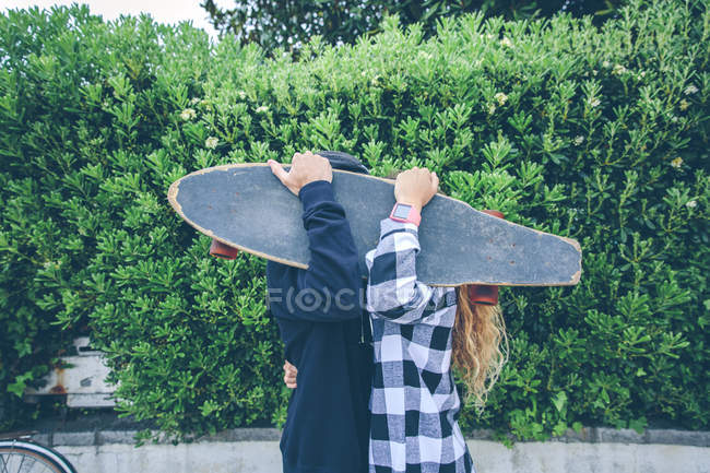 Пара ховається за скейтбордом — стокове фото