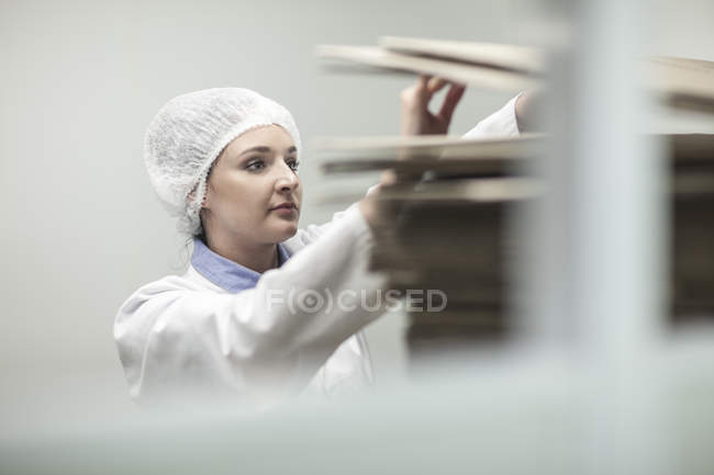 Mujer en ropa de trabajo protectora examinando cajas de cartón - foto de stock