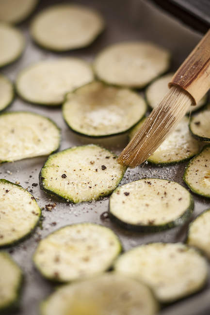 Slices of courgettes with spices on baking tray — Stock Photo