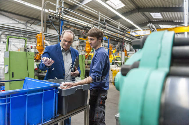 Manager and worker examining products in plastcs factory — Stock Photo