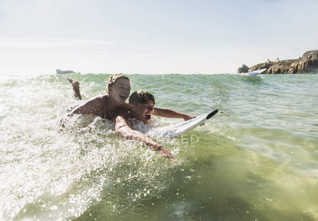 Deux amis s'amusent sur une planche de surf dans la mer — Photo de stock