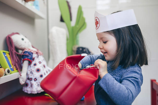 Bambina in cerca di giocattoli medici all'interno di una borsa rossa — Foto stock