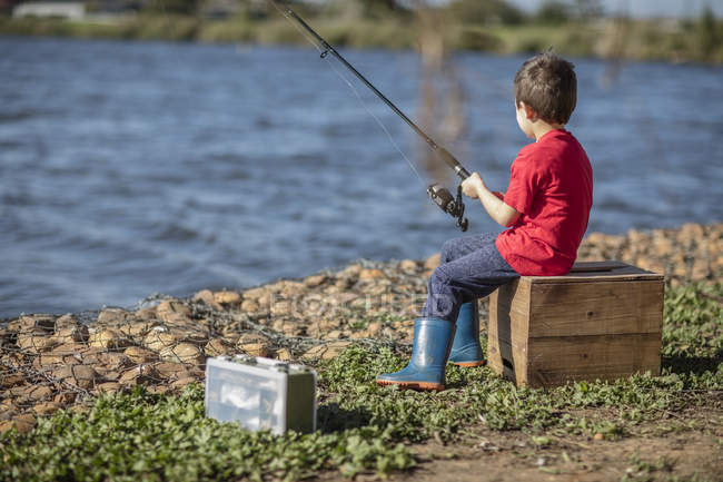 Caucásico niño pescando en el lago, vista trasera - foto de stock
