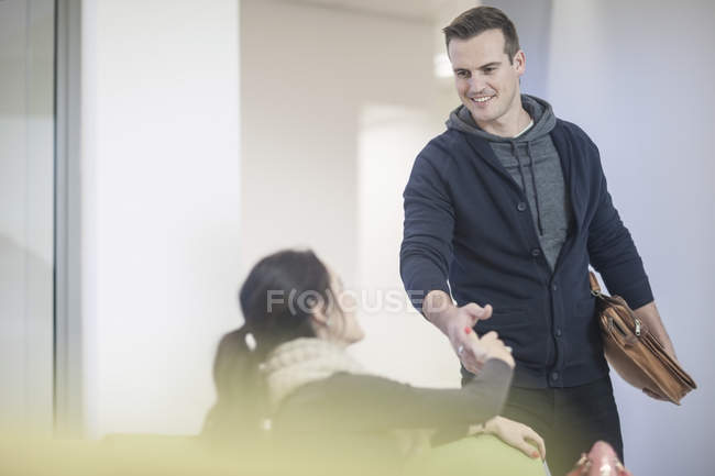 Mujer joven y hombre estrechando la mano en el vestíbulo - foto de stock