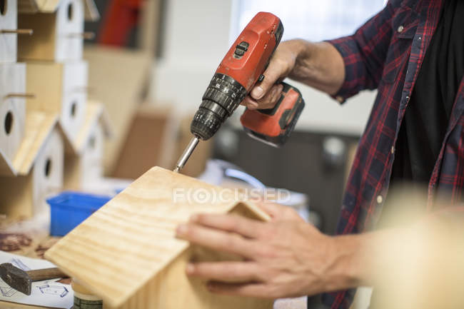Immagine ritagliata dell'uomo che lavora con trapano elettrico sulla casa degli uccelli in officina — Foto stock