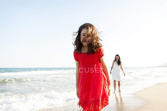 Щаслива маленька дівчинка на пляжі з матір'ю у фоновому режимі — стокове фото