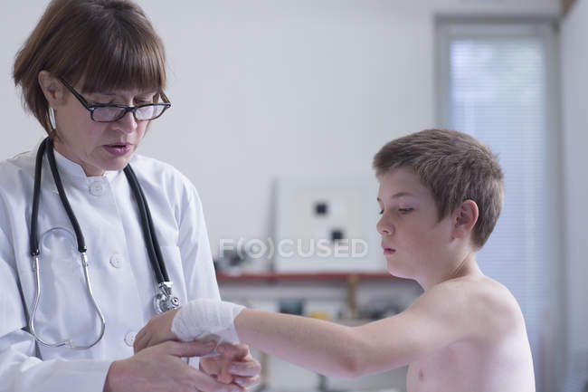 Médico vendaje brazo de niño en la práctica médica - foto de stock
