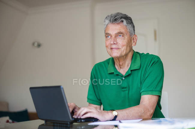 Senior man sitting at desk using laptop — Stock Photo