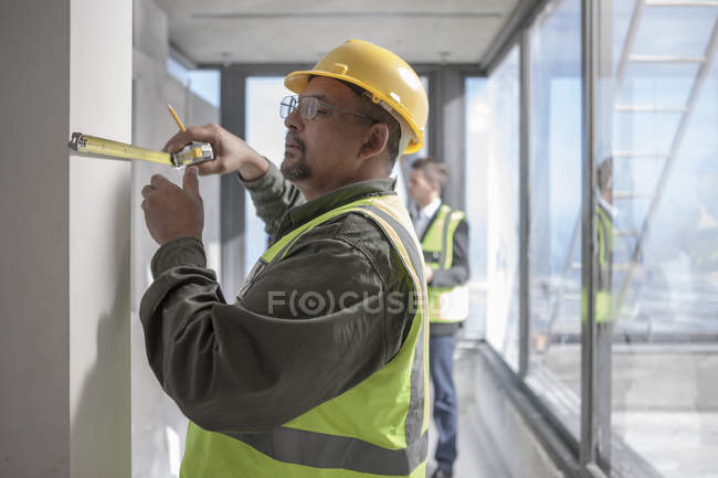 Construction worker measuring on construction site — Stock Photo