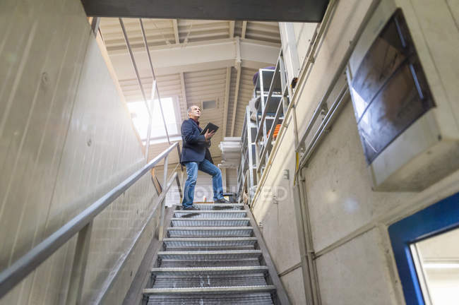 Manager steht auf Treppe und überprüft Waren im Lager — Stockfoto