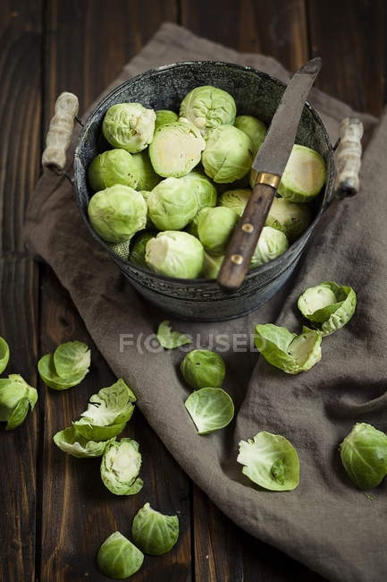 Peeled brussel sprouts in tin bucket, knife, studio shot — Stock Photo