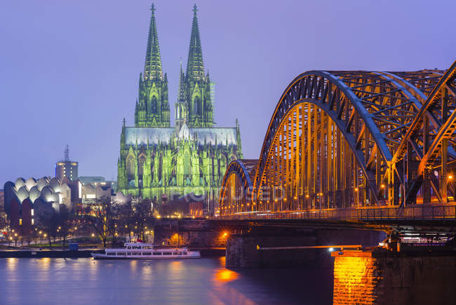 Germania, Colonia, veduta della cattedrale di Colonia illuminata con ponte Hohenzollern in primo piano — Foto stock