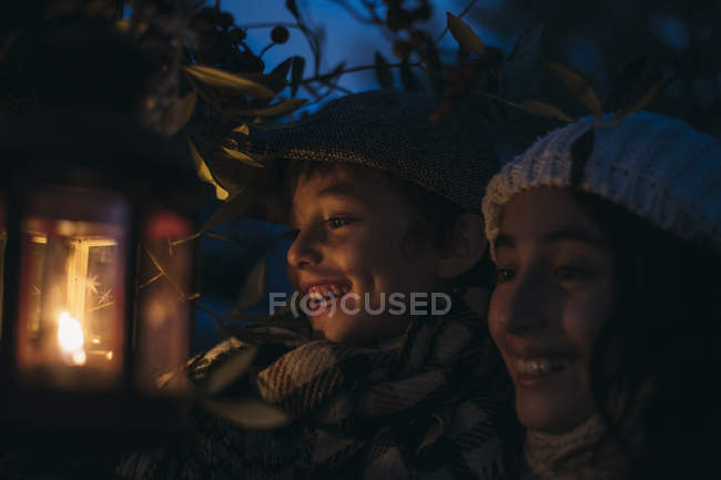 Laughing siblings with lighted Christmas lantern at night — Stock Photo