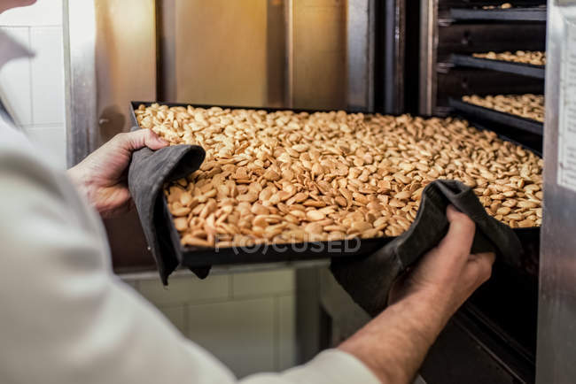 Close-up of chef removing roasted almonds on tray — Stock Photo
