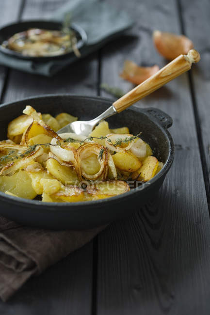 Pommes de terre frites avec rondelles d'oignon et thym dans la poêle — Photo de stock