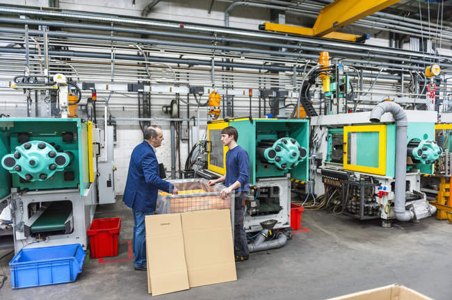 Gerente y trabajador en la fábrica de plásticos discutiendo la calidad de producción - foto de stock