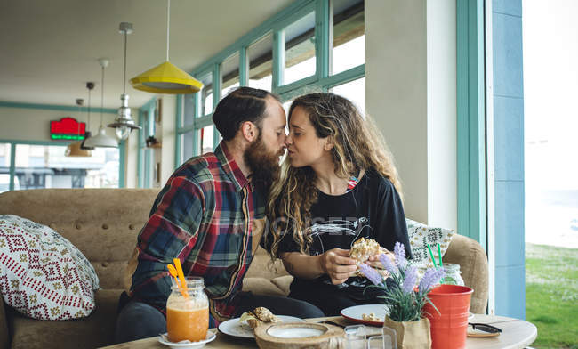 Couple kissing at breakfast in cafe — Stock Photo