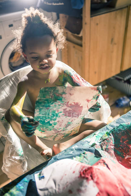 Mädchen zeichnet Bild mit Fingerfarben und ist vollständig von Farben verschmiert — Stockfoto
