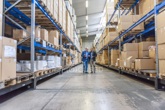 Two managers discussing packaging and shipment in storage hall — Stock Photo