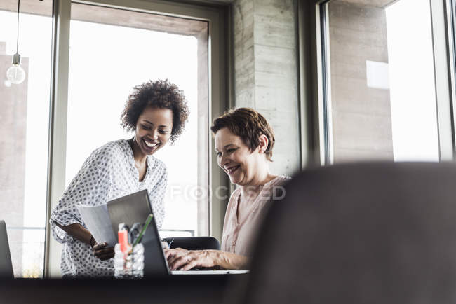Due donne sorridenti che lavorano insieme in ufficio — Foto stock