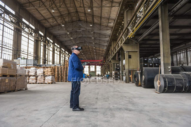 Manager steht in Fabrikhalle und blickt durch eine Brille — Stockfoto