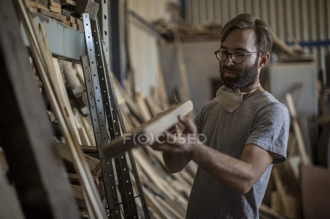 Falegname che guarda un pezzo di legno in officina — Foto stock