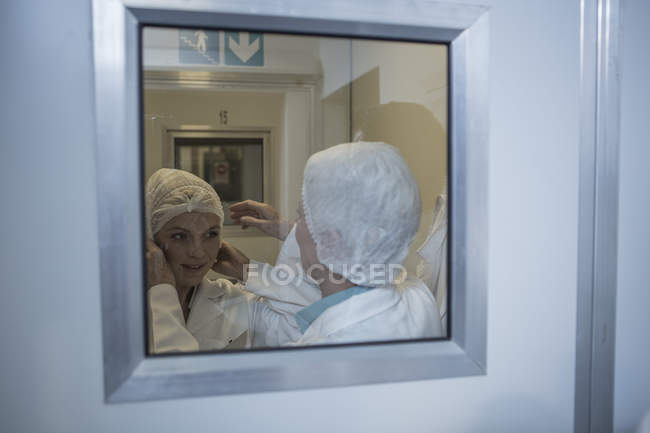 Deux techniciens de laboratoire revêtent des vêtements de protection stériles — Photo de stock