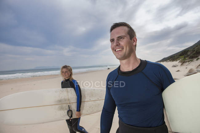 Счастливая молодая пара с досками для серфинга на пляже — стоковое фото