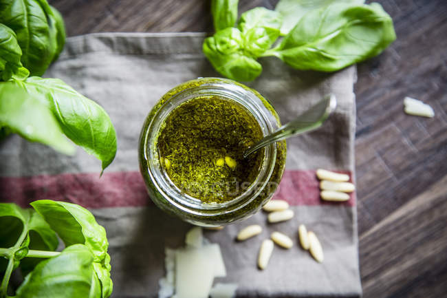 Glass of homemade pesto Genovese, pine nuts, basil leaves and parmesan on kitchen towel — Stock Photo
