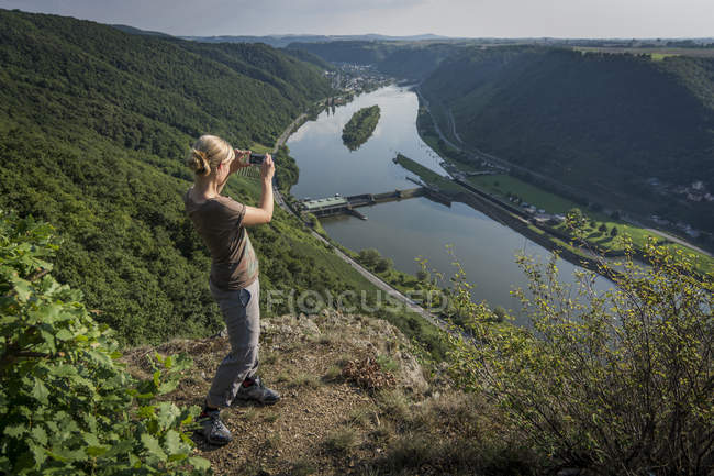 Alemania, Renania-Palatinado, Moselsteig, mujer fotografiando el río Mosela - foto de stock
