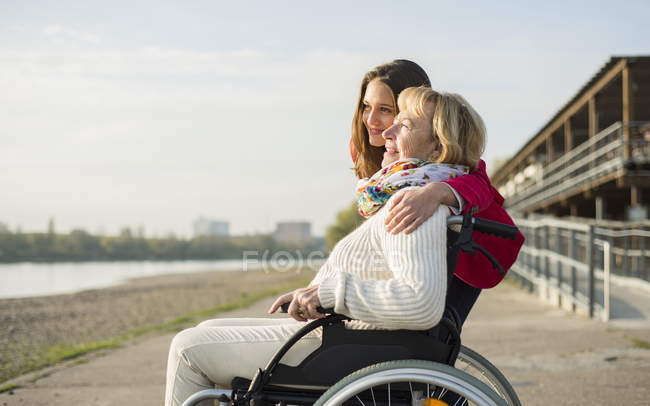 Внучка обнимает свою бабушку, сидя в инвалидном кресле — взрослые, Двачеловека - Stock Photo