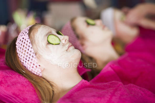 Mädchen auf einer Schönheitsfarm mit Gurken-Gesichtsmasken — Stockfoto