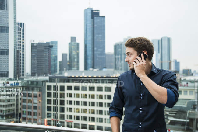 Німеччина, Гессен, Франкфурт, молода людина, тим, як телефонувати зі свого смартфона перед на skyline — стокове фото