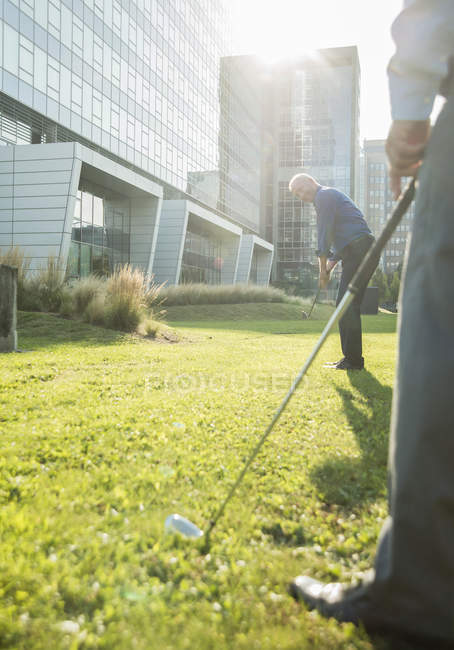 Zwei Geschäftsleute spielen Golf vor Bürogebäude — Stockfoto