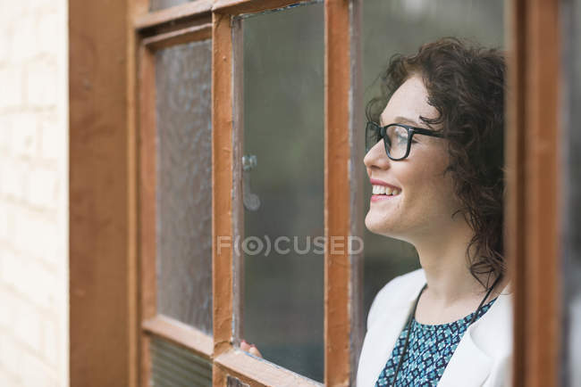 Sorrindo jovem empresária olhando pela janela — Fotografia de Stock
