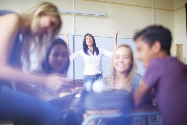 Frustrated teacher and talking students in classroom — Stock Photo