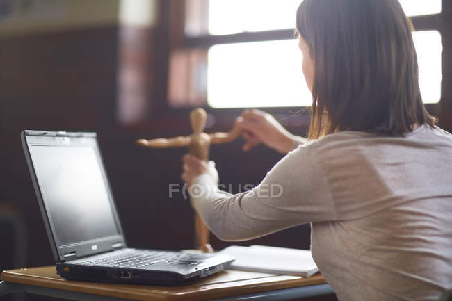Студентка в классе с ноутбуком и анатомической моделью — стоковое фото