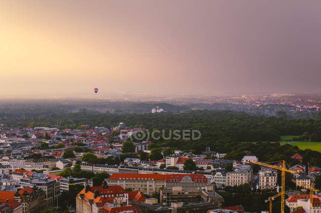 Hot air balloon hovering over the city at evening twilight, Leipzig, Germany — Stock Photo