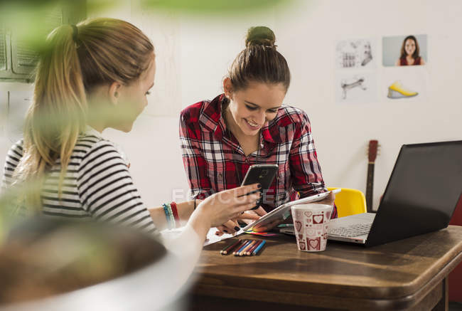 Deux amies avec smartphone, ordinateur portable et tablette numérique à la maison — Photo de stock