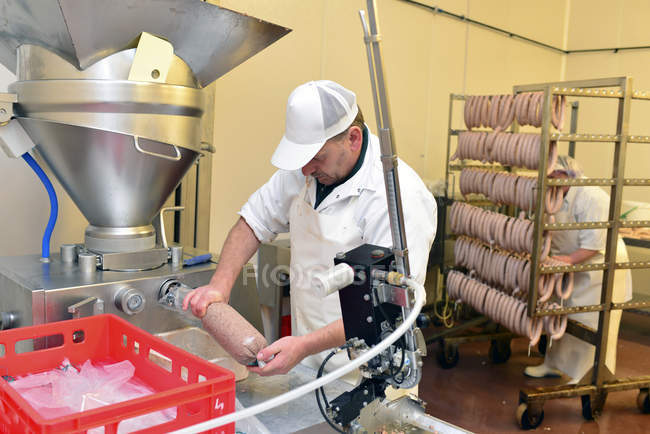 Uomo che lavora alla produzione di salsicce in una macelleria — Foto stock