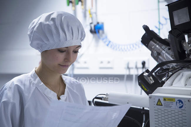 Jeune technicienne lisant les instructions dans un laboratoire — Photo de stock