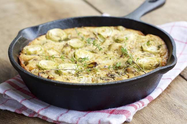 Brussels Sprout Frittata with leek and chickpea flour in frying pan on wood — Stock Photo