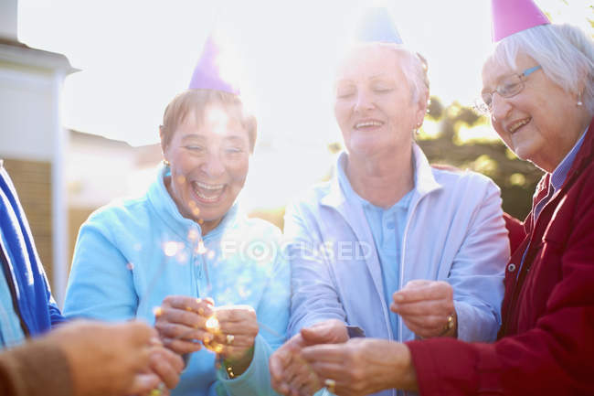 Senior friends lighting sparkler on a birthday garden party — Stock Photo
